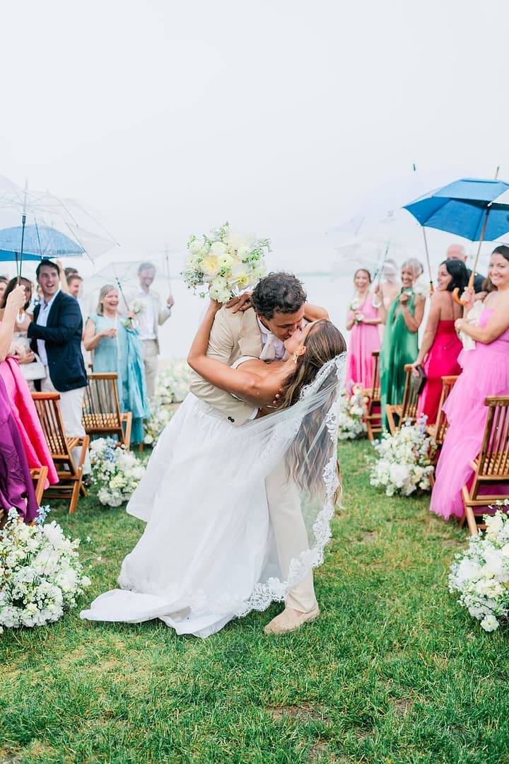 crows nest wedding Montauk where bride and groom are kissing after their ceremony showcasing aisle meadow arrangements and bridal bouquet